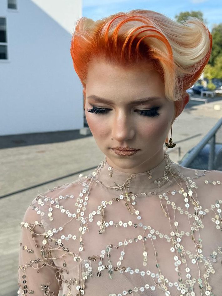 High-Fashion Styling Frau mit orangefarbenem, gestyltem Haar und eleganter Make-Up (Kosmetik).